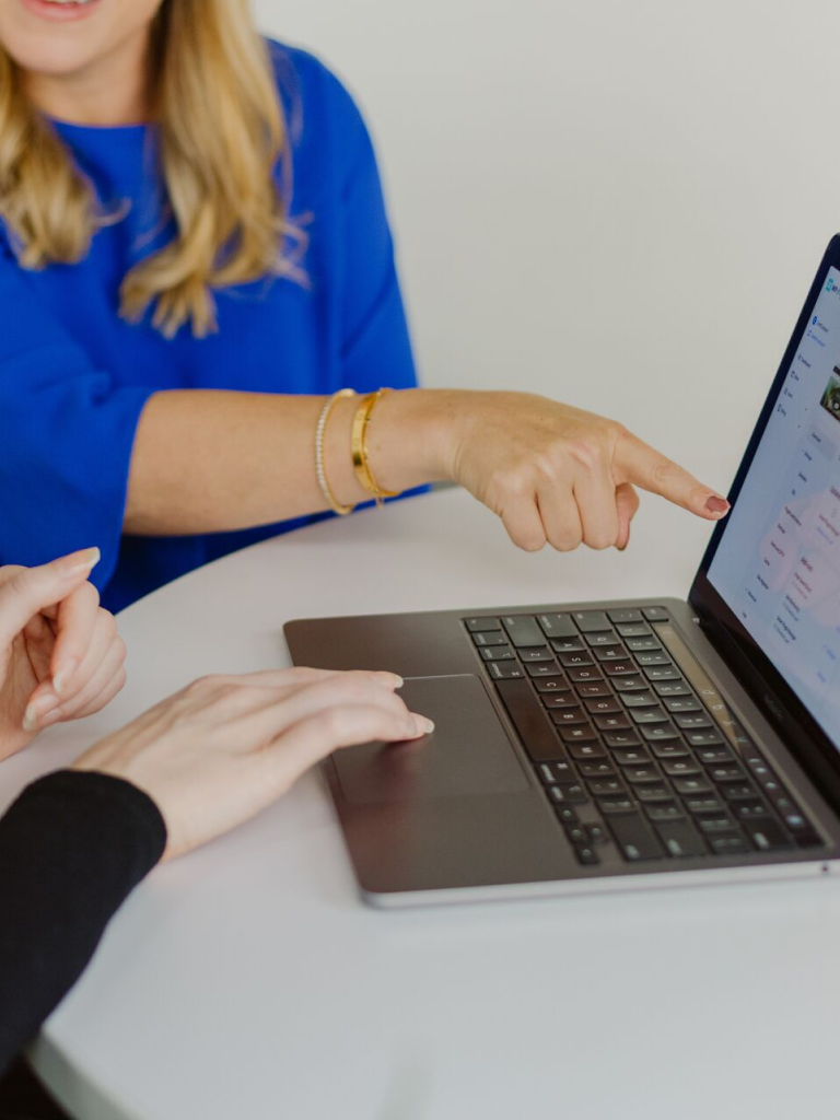 two people pointing at laptop and talking
